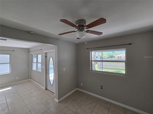 empty room featuring a wealth of natural light, baseboards, and light tile patterned floors