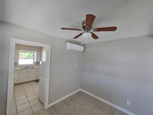 empty room with light tile patterned flooring, a sink, a ceiling fan, a wall unit AC, and baseboards