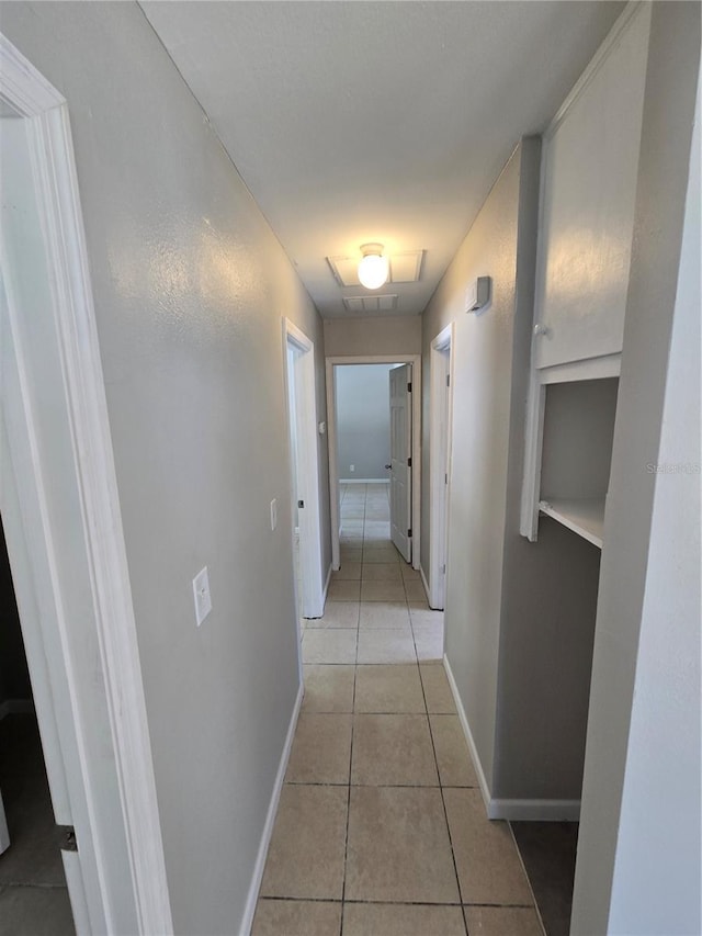 corridor featuring light tile patterned flooring and baseboards
