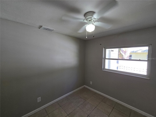 tiled spare room with baseboards, ceiling fan, and visible vents