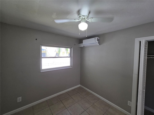 empty room featuring a ceiling fan, light tile patterned floors, baseboards, and a wall mounted air conditioner