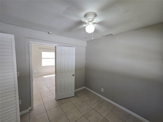 unfurnished room with a ceiling fan, light tile patterned flooring, baseboards, and visible vents