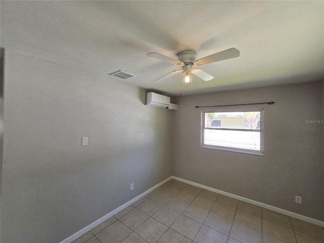 empty room with a ceiling fan, a wall unit AC, light tile patterned floors, baseboards, and visible vents