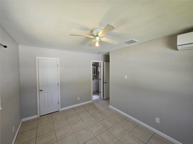 empty room with a wall unit AC, light tile patterned floors, baseboards, visible vents, and ceiling fan