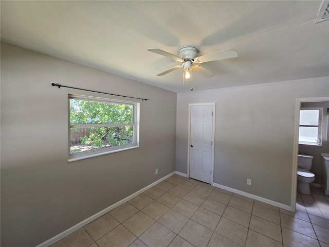 empty room with baseboards, visible vents, light tile patterned floors, and a ceiling fan