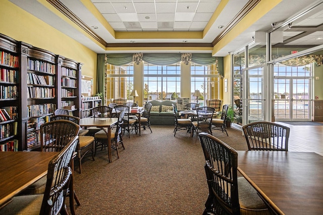 dining space featuring a raised ceiling, carpet floors, and a towering ceiling