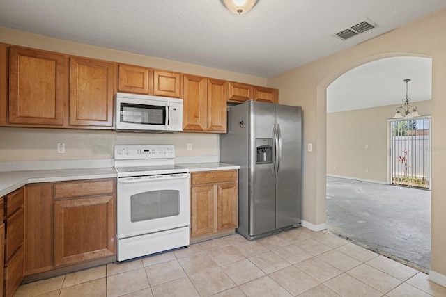 kitchen featuring hanging light fixtures, white appliances, light tile patterned floors, and a textured ceiling