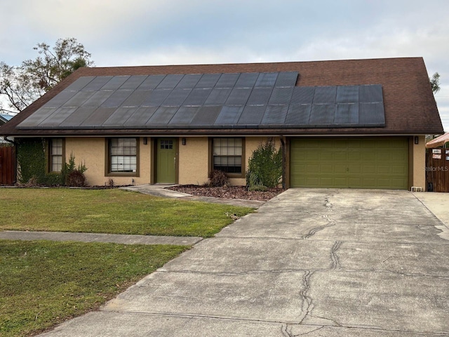 view of front of property with a front yard, solar panels, and a garage