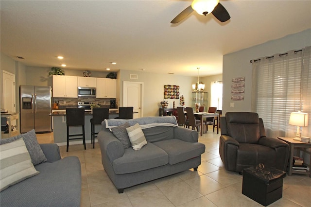 tiled living room with ceiling fan with notable chandelier