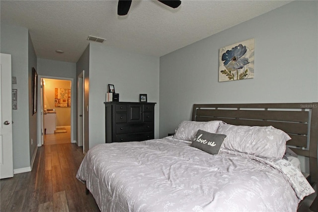 bedroom with a textured ceiling, ensuite bathroom, ceiling fan, and dark wood-type flooring