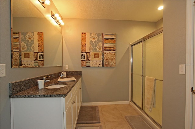 bathroom with tile patterned flooring, vanity, a shower with door, and a textured ceiling