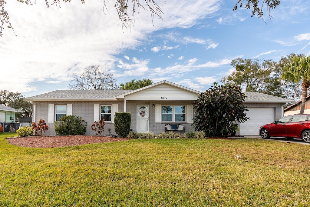 ranch-style home with a garage and a front lawn