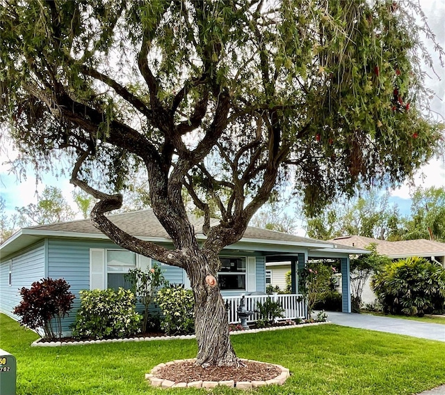 ranch-style home with driveway, covered porch, a shingled roof, and a front lawn