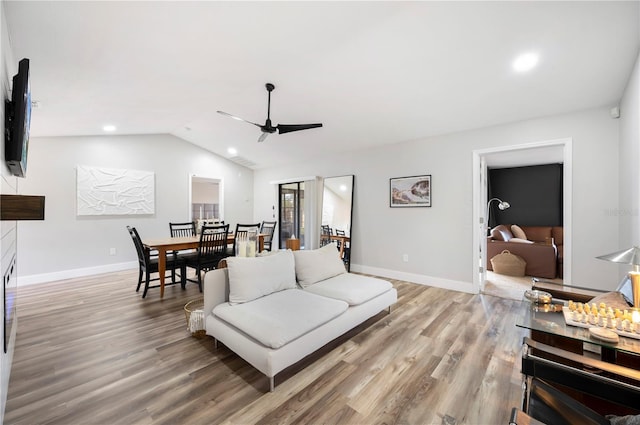 living room with light hardwood / wood-style flooring, vaulted ceiling, and ceiling fan