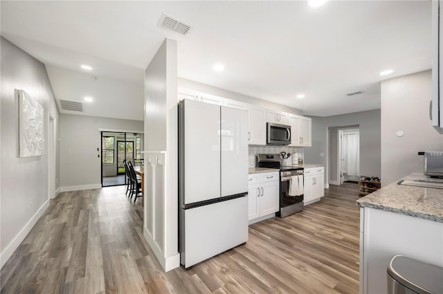 kitchen featuring stainless steel appliances, light stone countertops, white cabinets, decorative backsplash, and light wood-type flooring