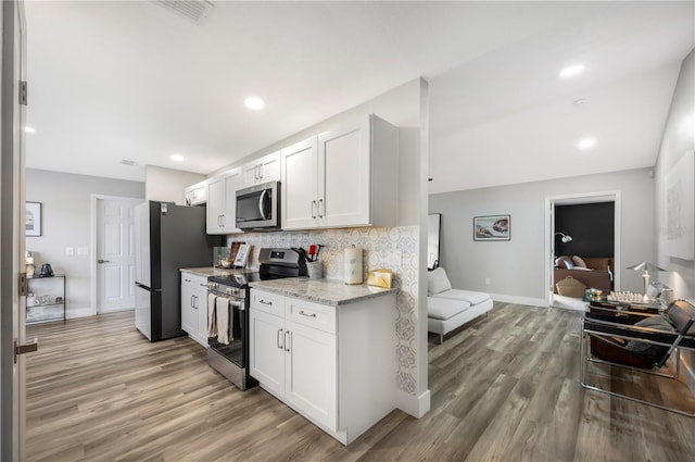 kitchen featuring stainless steel appliances, light wood-type flooring, white cabinets, and backsplash