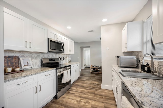 kitchen featuring sink, stainless steel appliances, light stone counters, white cabinets, and decorative backsplash