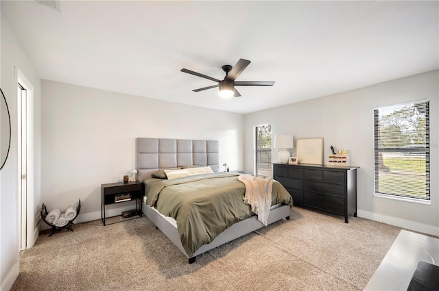 bedroom featuring multiple windows, light colored carpet, and ceiling fan