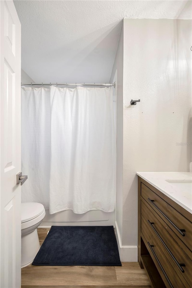 full bathroom featuring hardwood / wood-style flooring, vanity, toilet, and a textured ceiling