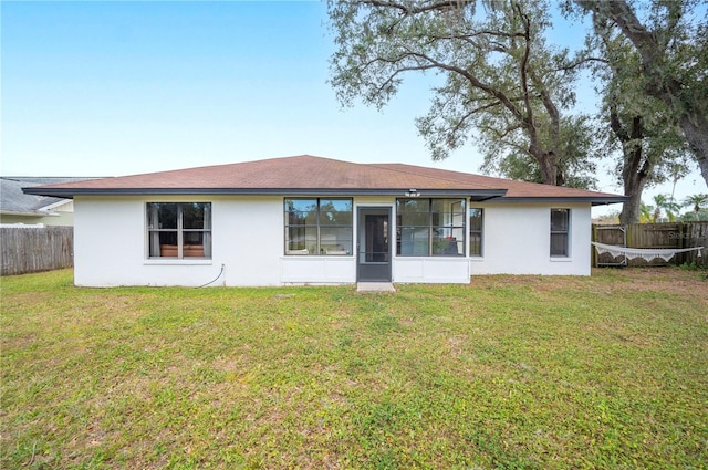 rear view of property featuring a yard and a sunroom