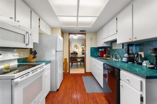 kitchen with sink, tasteful backsplash, hardwood / wood-style floors, white appliances, and white cabinets