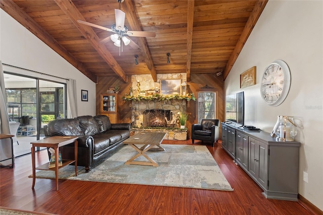 living room with lofted ceiling with beams, a stone fireplace, ceiling fan, dark hardwood / wood-style flooring, and wood ceiling