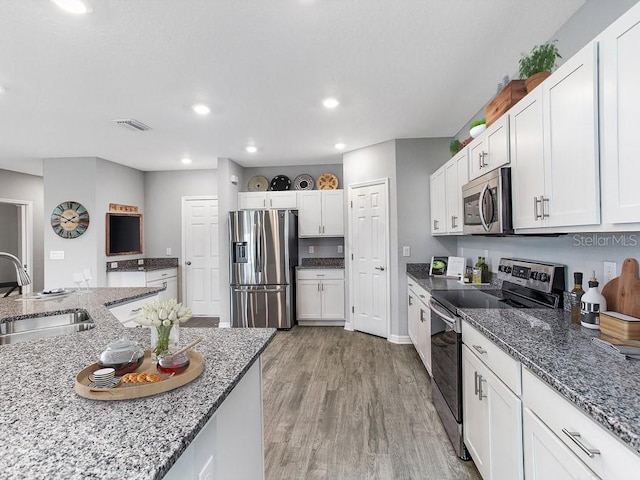 kitchen with hardwood / wood-style flooring, sink, white cabinetry, and stainless steel appliances