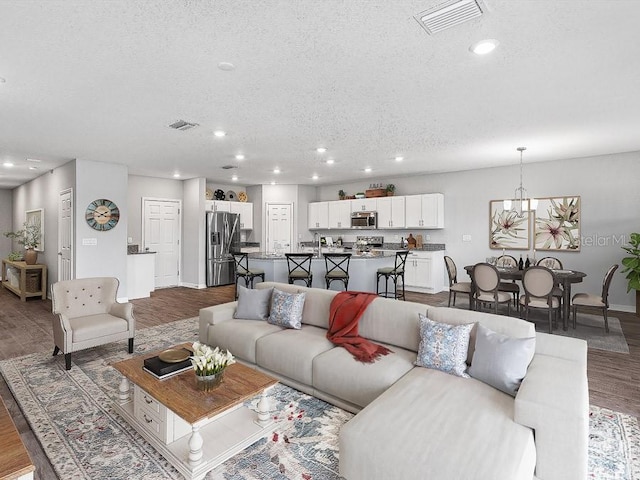 living room featuring hardwood / wood-style flooring, a notable chandelier, and a textured ceiling