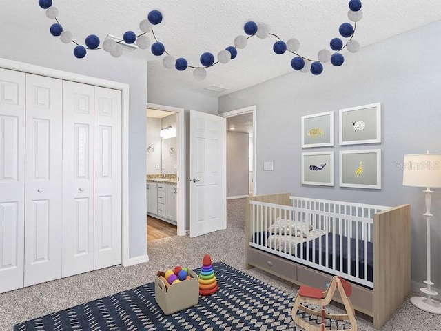 bedroom with carpet, a textured ceiling, and a nursery area