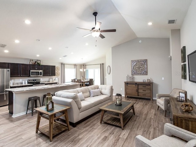 living room featuring ceiling fan, lofted ceiling, and light wood-type flooring