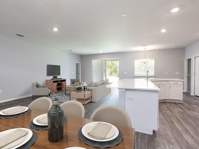 interior space with a center island with sink, white cabinets, hanging light fixtures, and light hardwood / wood-style flooring