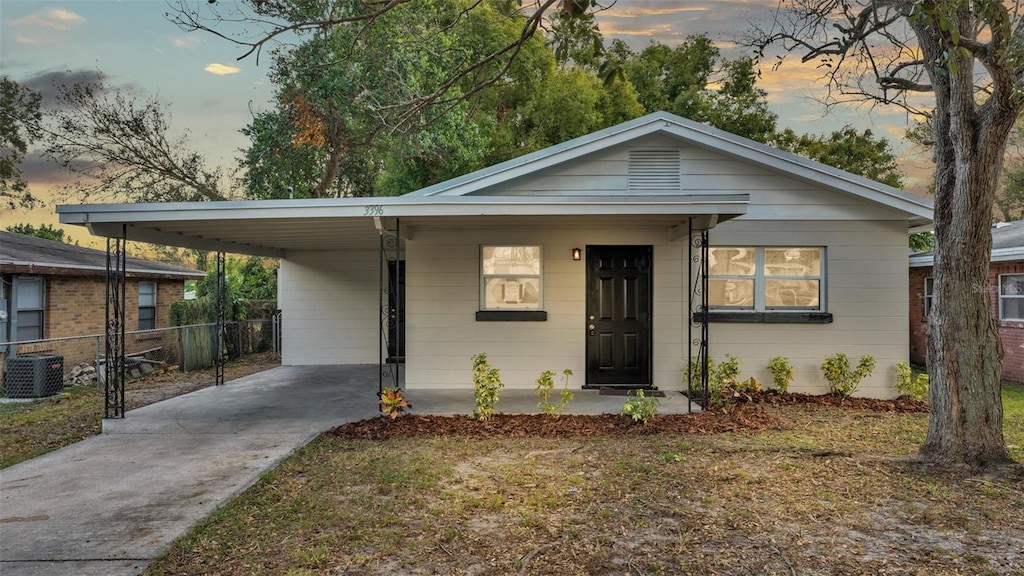 view of front of property featuring a lawn, central AC, and a carport