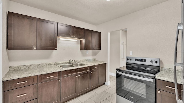 kitchen with electric range, sink, a textured ceiling, dark brown cabinets, and light tile patterned floors