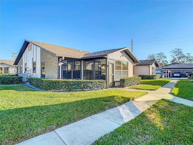 view of property exterior featuring a lawn, a sunroom, and a carport