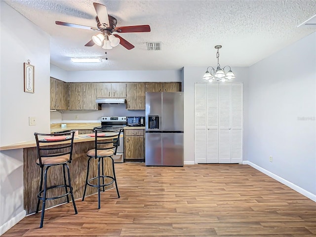 4531 Blossom Blvd Unit 4531, Zephyrhills, FL 33542 - kitchen featuring pendant lighting, a breakfast bar, ceiling fan with notable chandelier, a textured ceiling, and stainless steel appliances