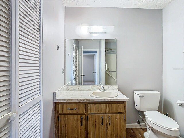 4531 Blossom Blvd Unit 4531, Zephyrhills, FL 33542 - bathroom featuring a textured ceiling, vanity, hardwood / wood-style flooring, and toilet