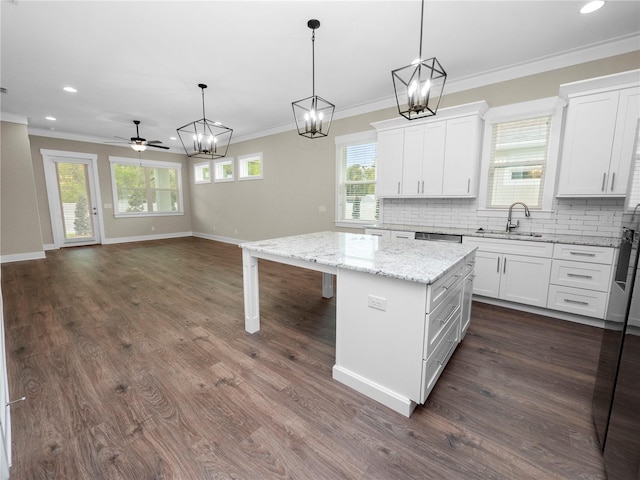 kitchen with ceiling fan, sink, white cabinets, a center island, and hanging light fixtures