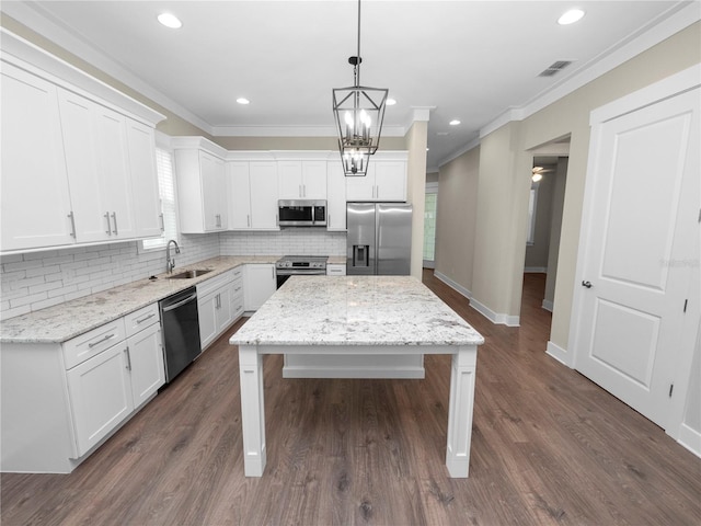 kitchen featuring appliances with stainless steel finishes, a center island, white cabinetry, and light stone counters