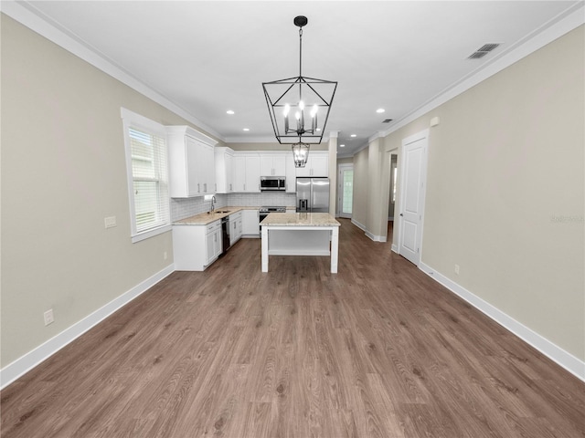 kitchen with a center island, tasteful backsplash, decorative light fixtures, white cabinetry, and stainless steel appliances