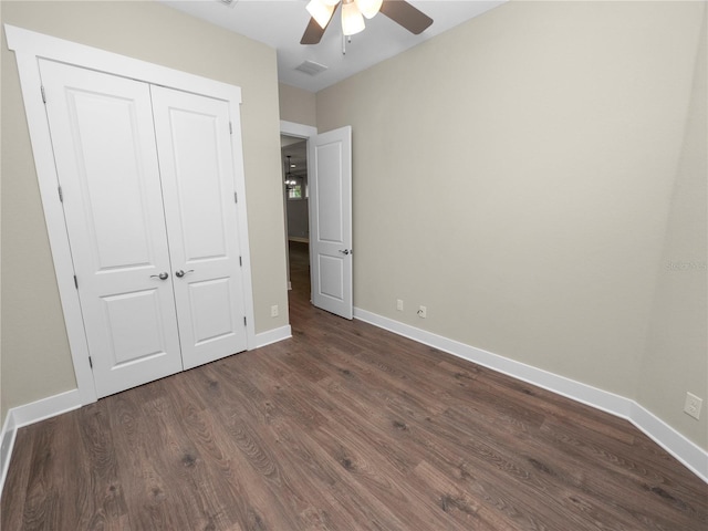 unfurnished bedroom featuring ceiling fan, a closet, and dark wood-type flooring