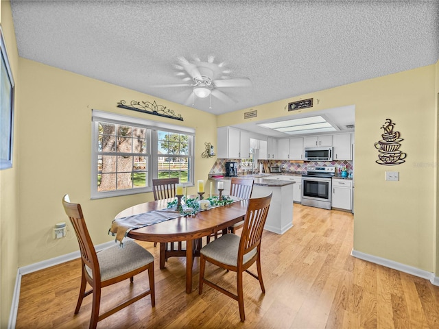 dining space with ceiling fan, a textured ceiling, and light wood-type flooring