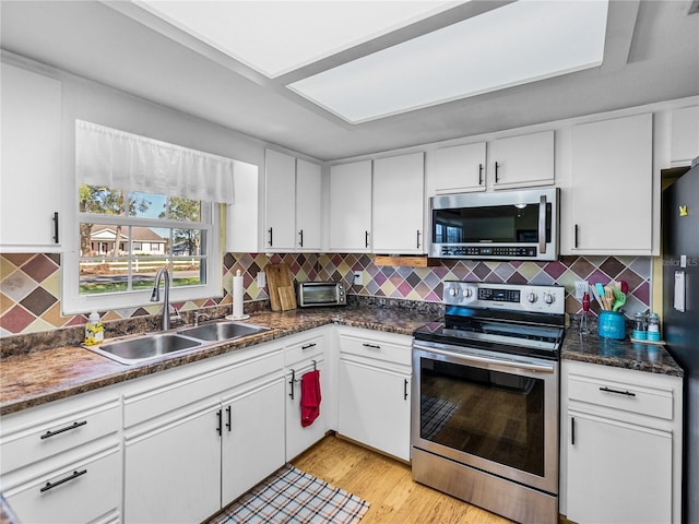 kitchen with light wood-type flooring, stainless steel appliances, white cabinetry, and sink