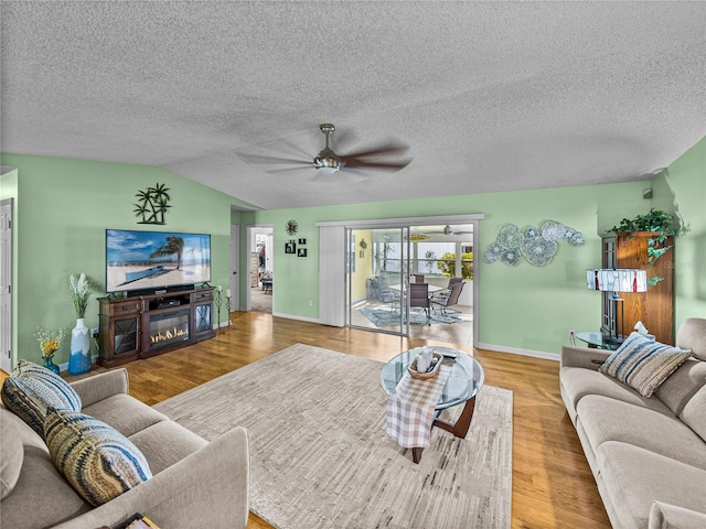 living room featuring hardwood / wood-style floors, ceiling fan, lofted ceiling, and a textured ceiling