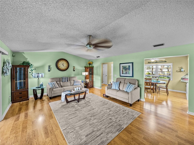 living room featuring ceiling fan, light wood-type flooring, and vaulted ceiling