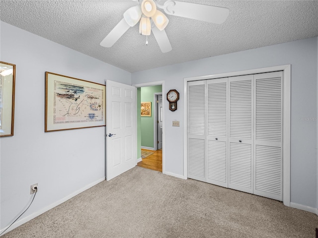 unfurnished bedroom with a textured ceiling, a closet, ceiling fan, and light colored carpet