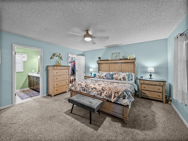 bedroom with carpet, ensuite bathroom, a walk in closet, ceiling fan, and a closet