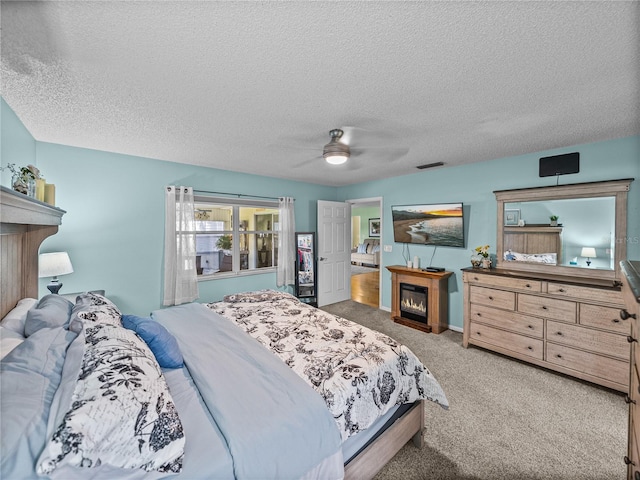 carpeted bedroom featuring ceiling fan and a textured ceiling