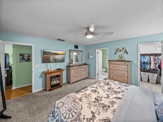 bedroom featuring ensuite bath, ceiling fan, a spacious closet, light carpet, and a closet