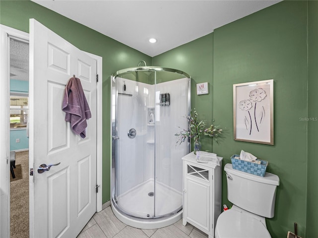 bathroom featuring tile patterned floors, toilet, and a shower with shower door