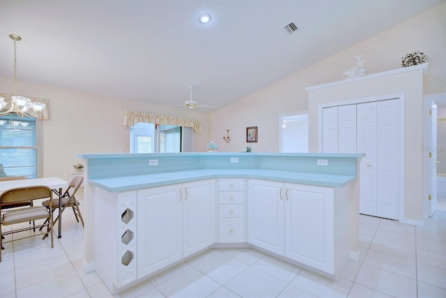 kitchen with hanging light fixtures, a kitchen island, white cabinets, light tile patterned floors, and ceiling fan with notable chandelier